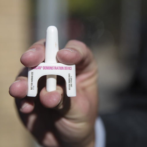 A person holding a Narcan nasal inhaler up close for the camera.
