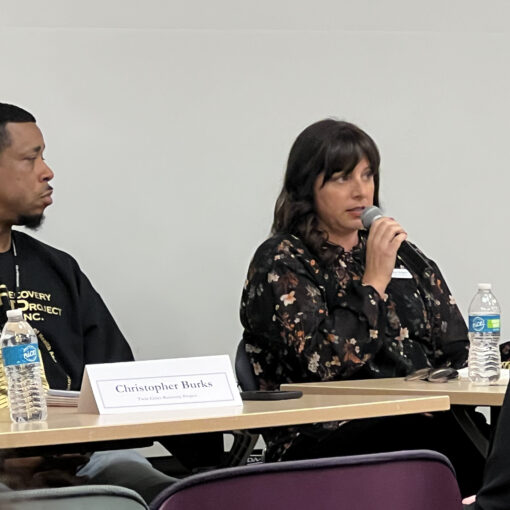 Megan at DOJ speaking on a microphone during a panel presention